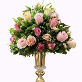 Pink and cream roses arranged in a tall gold vase