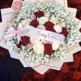 Bouquet of red, white, and blush roses with baby's breath and a pink ribbon