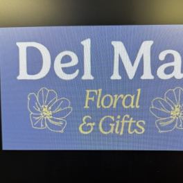 Blue sign reading Del Mar Floral & Gifts with flower outlines