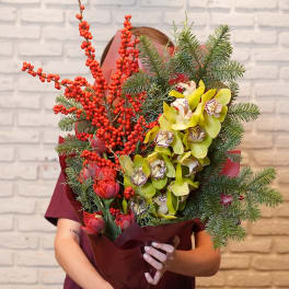 Bouquet of red berries, yellow orchids, and evergreen branches