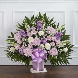 Standing floral spray with pink and white flowers and a purple ribbon bow