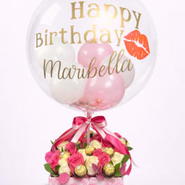 Birthday balloon over pink and white roses with chocolates in a floral box