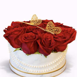Round box of red roses topped with gold butterfly decorations