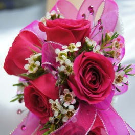 Pink rose wrist corsage with ribbon and small white flowers
