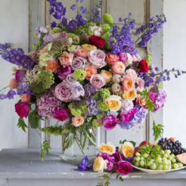 Large mixed bouquet of roses and purple flowers in a glass vase