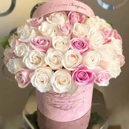 Pink and white roses arranged in a round pink hat box