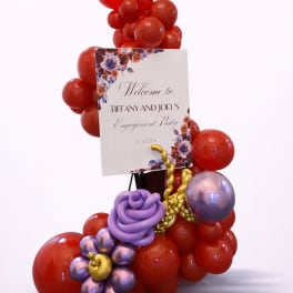 Red and purple balloon display with an engagement party sign