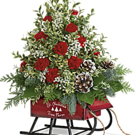 Christmas arrangement in a red sleigh with red carnations and pinecones