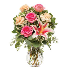Bouquet of pink roses, lilies, and peach carnations in a glass vase