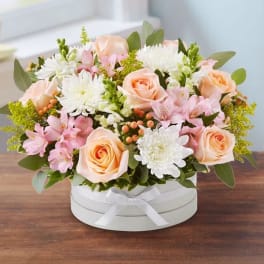 Round bouquet of peach roses, white chrysanthemums, and pink flowers in a white box