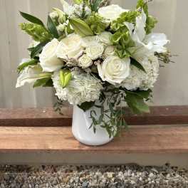 White roses and lilies arranged in a white vase