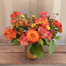 Orange roses and pink carnations in a gold vase
