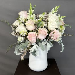 Pink and white roses arranged in a white vase
