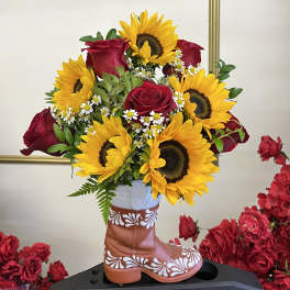 Sunflowers and red roses arranged in a decorative boot vase