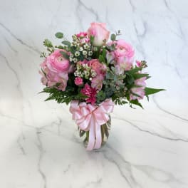 Pink mixed flower bouquet in a glass vase with a ribbon