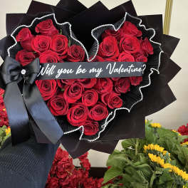 Heart-shaped bouquet of red roses with a black ribbon and Valentine message