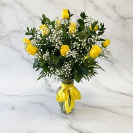 Yellow roses and baby's breath in a glass vase with a yellow ribbon