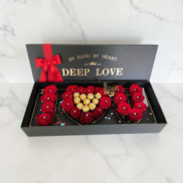 Red roses and chocolates arranged in a black gift box