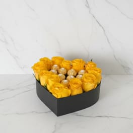 Heart-shaped box of yellow roses with chocolates in the center