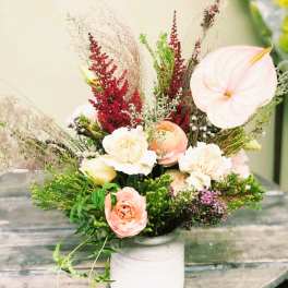 Mixed floral arrangement in a white vase with pale pink and cream blooms