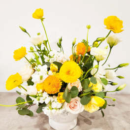 Yellow and white floral arrangement in a white vase