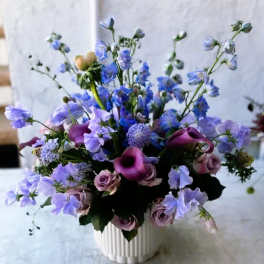 Purple and blue mixed bouquet in a white vase