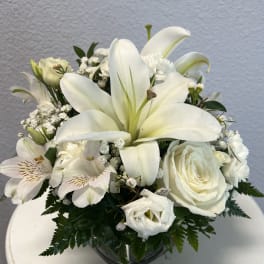 White lilies and roses arranged in a glass vase