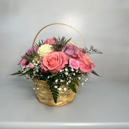 Basket of pink, cream, and lavender roses with baby's breath