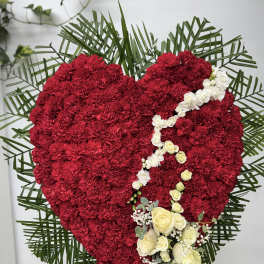 Heart-shaped red floral tribute with white roses and palm fronds