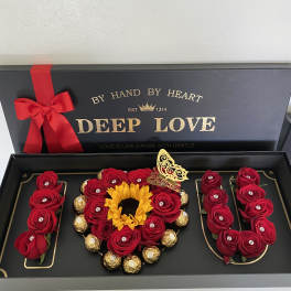 Gift box with red roses, a sunflower, and chocolates arranged in the shape of "I LOVE U"