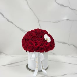 Round bouquet of red roses in a white hat box with white orchids