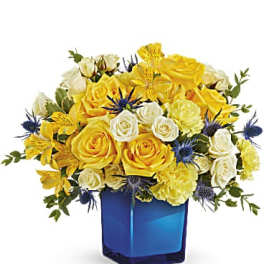 Yellow and white rose bouquet in a blue glass vase