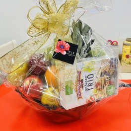 Gift basket with fruit and snack packages wrapped in clear cellophane and a gold bow