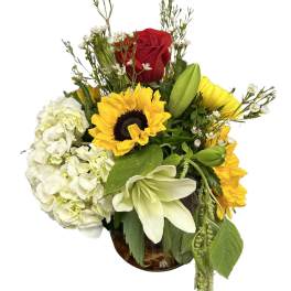Bouquet of sunflowers, white hydrangea, and a red rose in a glass vase