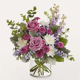 Pink roses and purple-white flowers in a clear glass vase
