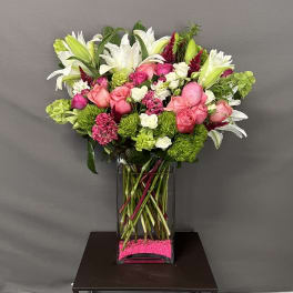 Mixed bouquet of pink and white flowers in a tall glass vase
