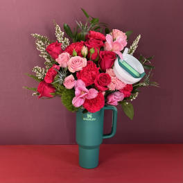 Pink and red rose bouquet arranged in a teal Stanley tumbler