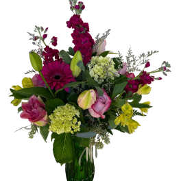 Mixed bouquet of pink, yellow, and green flowers in a glass vase