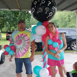 People holding colorful balloons under a covered patio