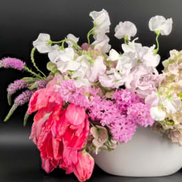 Pink and white floral arrangement in a white bowl vase