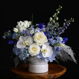 White and blue floral arrangement in a white vase