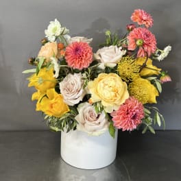 Mixed bouquet of pink, yellow, and white flowers in a white box