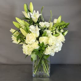 White lilies and roses arranged in a clear glass vase