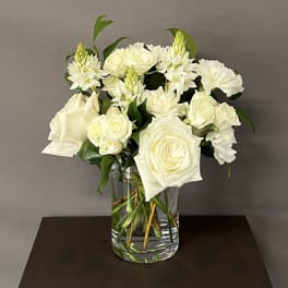 White roses and carnations arranged in a clear glass vase