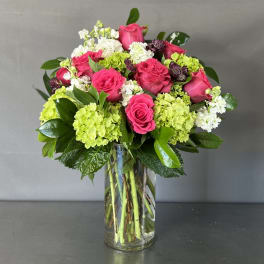 Pink roses and green hydrangeas arranged in a clear glass vase.
