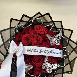 Bouquet of red roses with a white ribbon and butterfly decorations