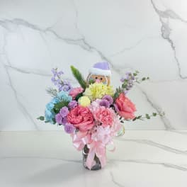 Colorful bouquet in a glass vase with a small festive doll topper