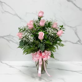 Pink roses in a glass vase with a pink ribbon bow