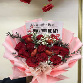 Bouquet of red roses with pink wrapping and a Valentine card
