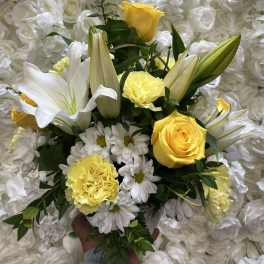 Yellow roses and white lilies with daisies in a hand-tied bouquet
